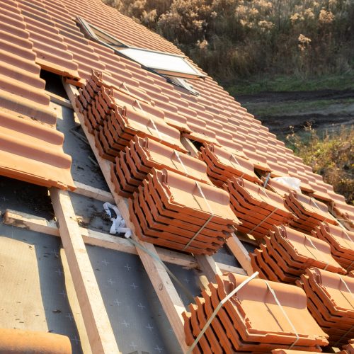 Stacks of yellow ceramic roofing tiles for covering residential building roof under construction.